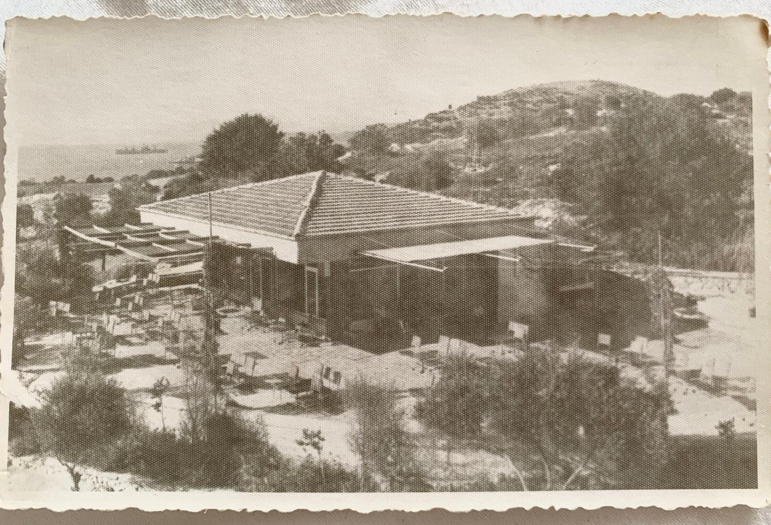 Kadınlar Denizi'ndeki ilk bina — kiremit çatılı yapı, arkada deniz; dönem baskısı
