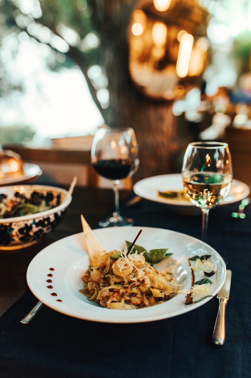 A garden table at golden hour: seafood pasta and wine